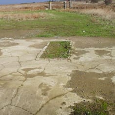 Looking towards the entrance of Camp Sylt from the well-preserved hut base of one of the SS Barracks occupying a compound in front of the gates.